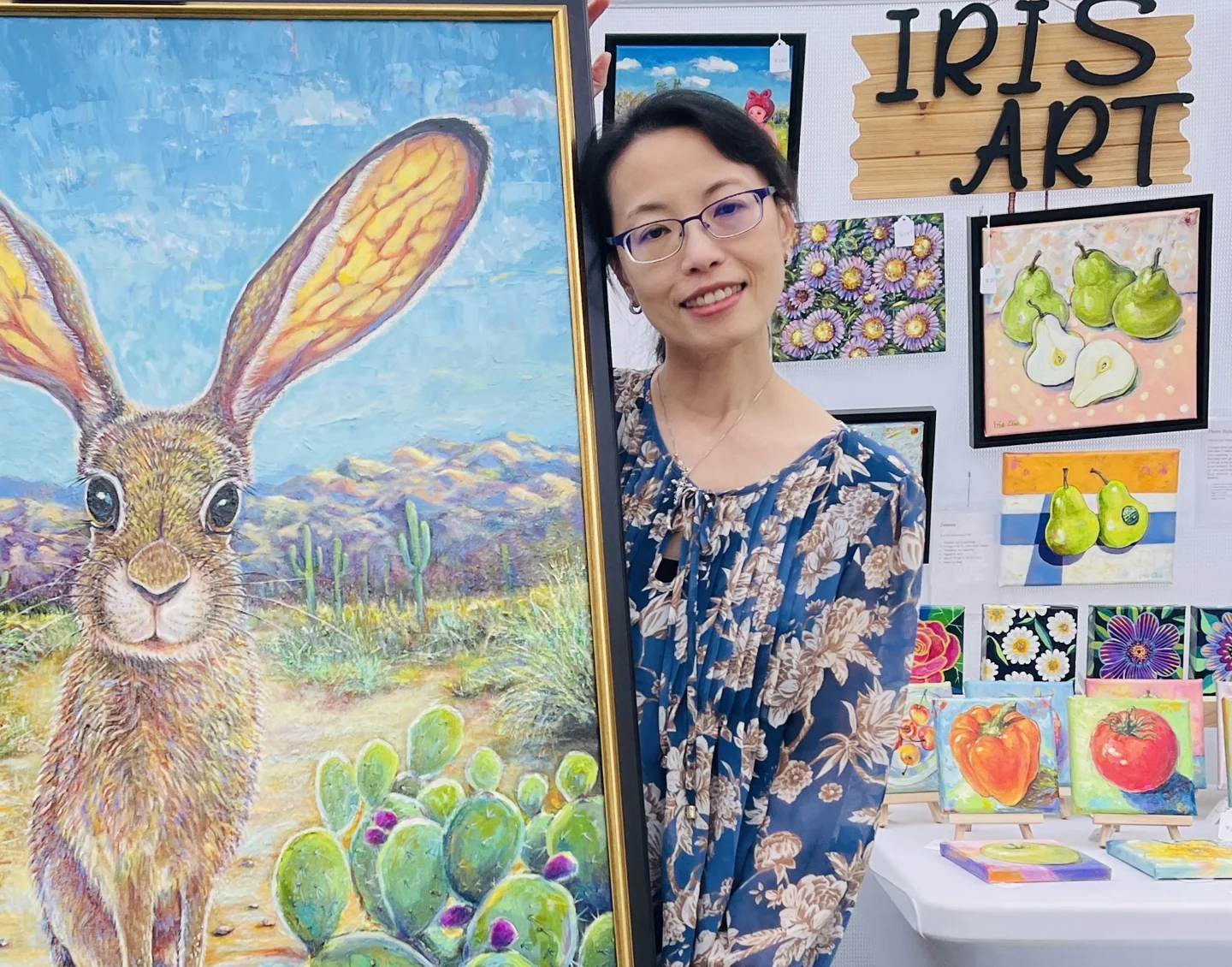 Iris beside a large rabbit painting, surrounded by her artwork.